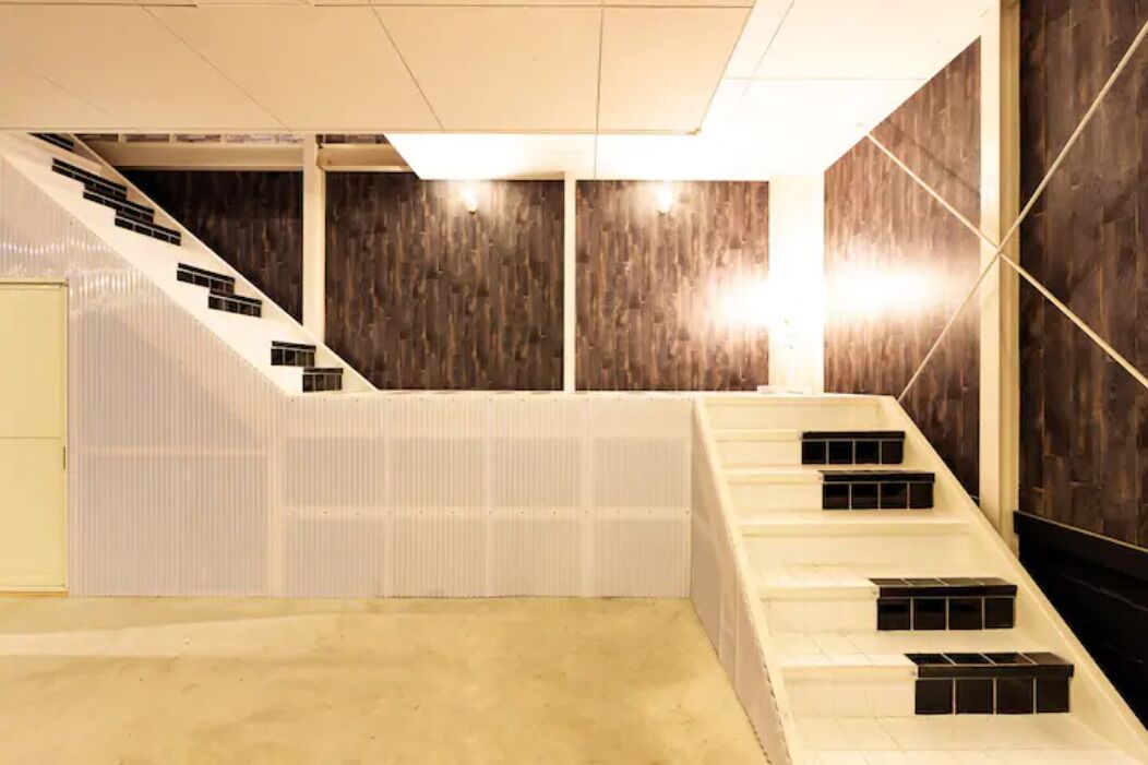 A modern interior with a staircase, wooden panel walls, and a light-colored floor.