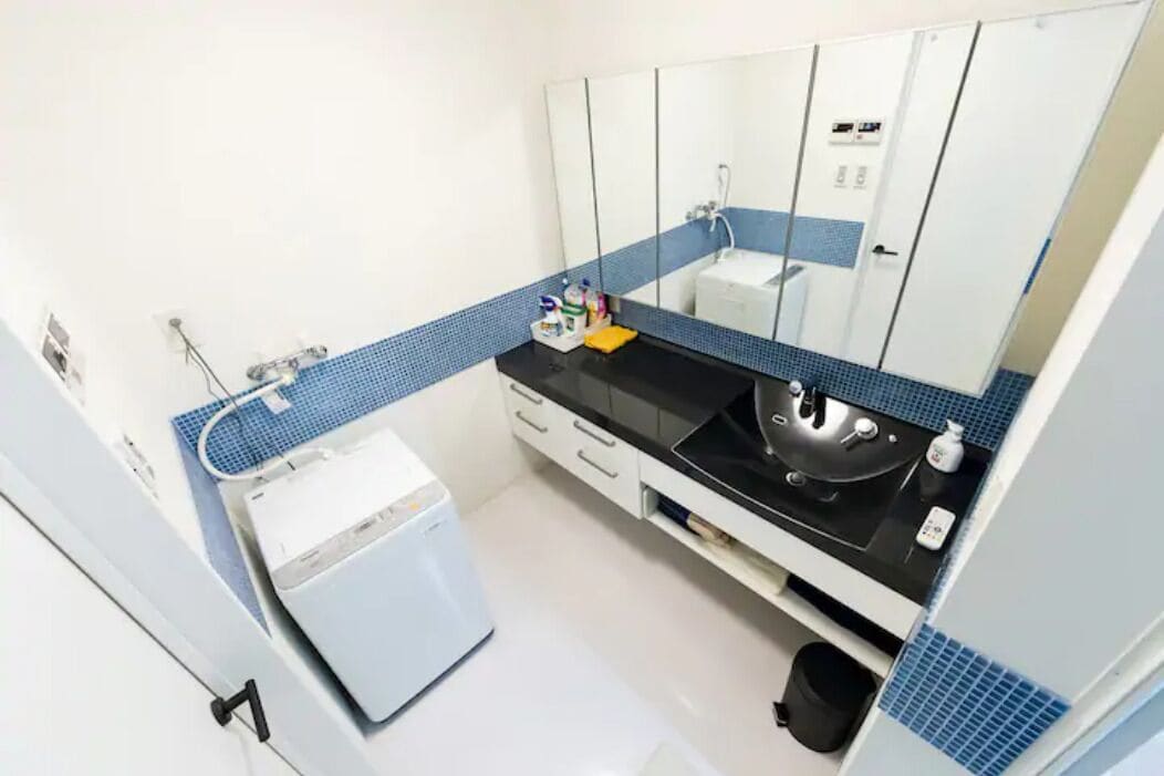 A modern bathroom with a black countertop, white sink, and blue-tiled walls.