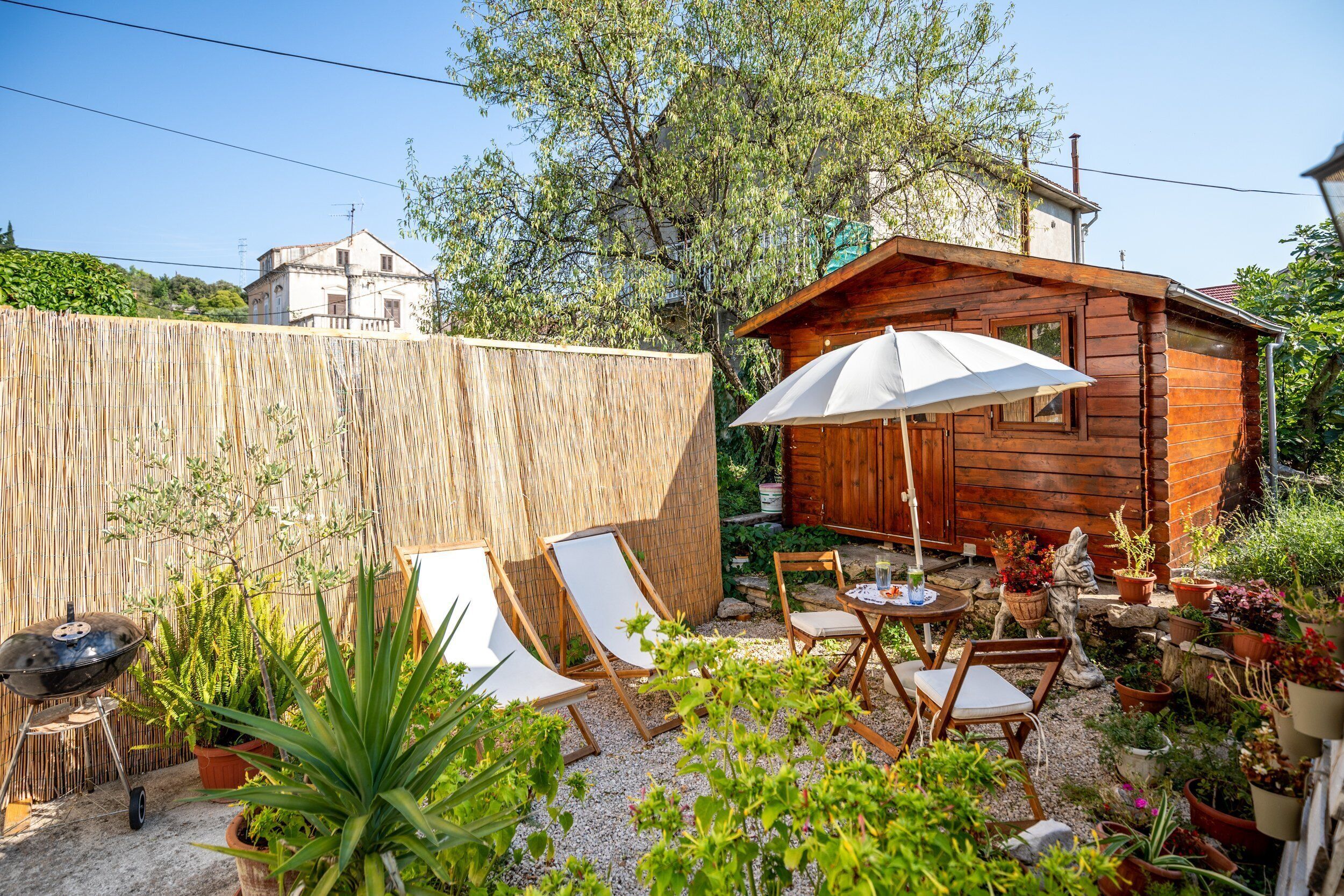 Een houten chalet met een terras, inclusief een tafel, stoelen en een parasol.