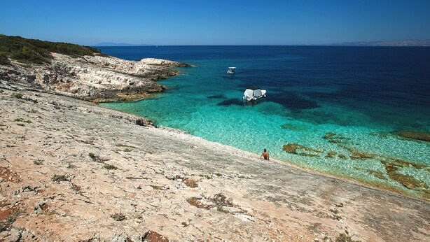 A rocky coastline with clear turquoise waters and a distant boat. - Stone House Harmony (Korcula)