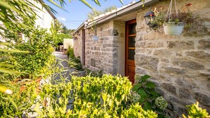 A stone building with a wooden door, potted plants, and a small garden area. - Stone House Harmony (Korcula)