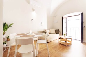 A modern living room with a round table, white chairs, a sofa, and a balcony. - Apartments Plaza Mayor 35 (Cáceres‎)