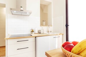 A modern kitchen with white cabinetry, a built-in dishwasher, and a wooden countertop. - Apartments Plaza Mayor 35 (Cáceres‎)
