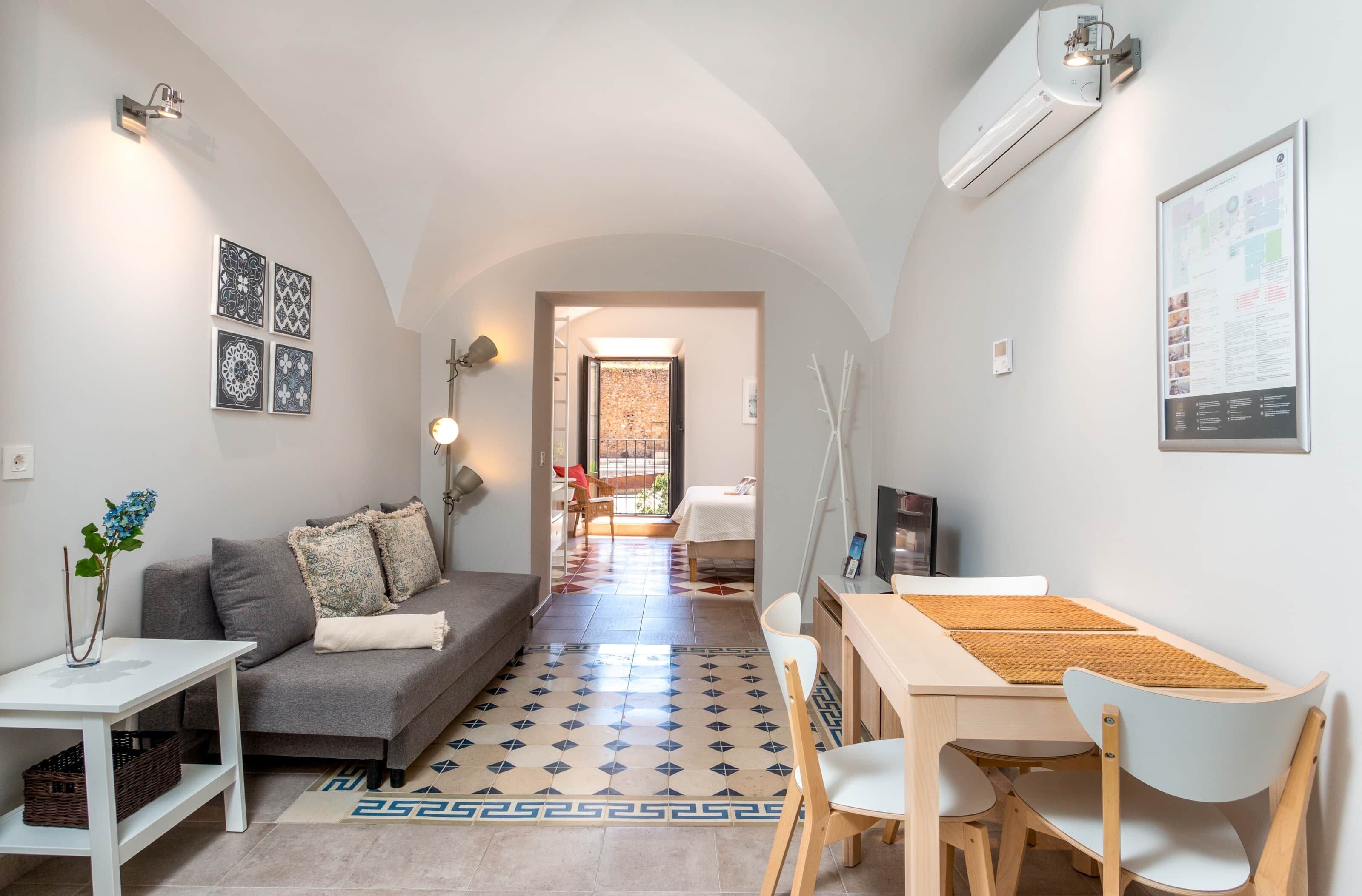 Un salon moderne avec un canapé, une table à manger et des chaises. Un couloir mène à une autre pièce.