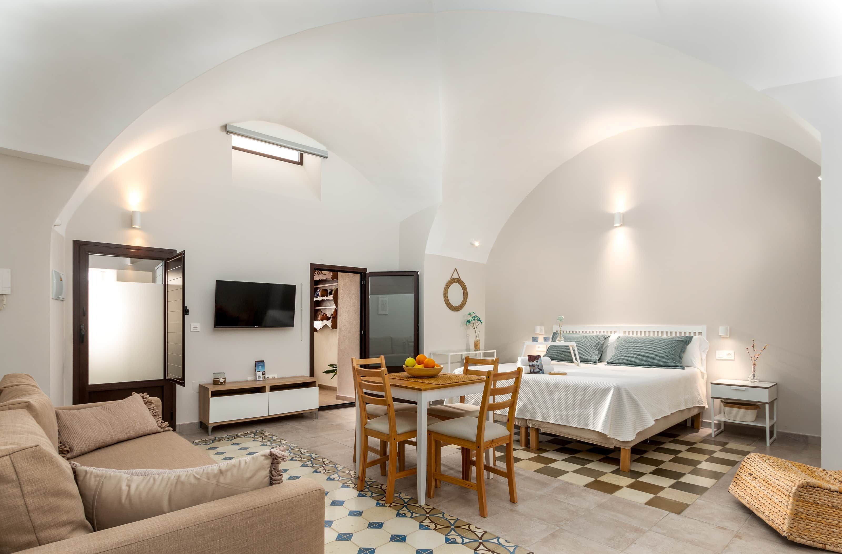 Ein kompakter Wohnbereich mit Essplatz, Sofa, Bett und Fernseher.