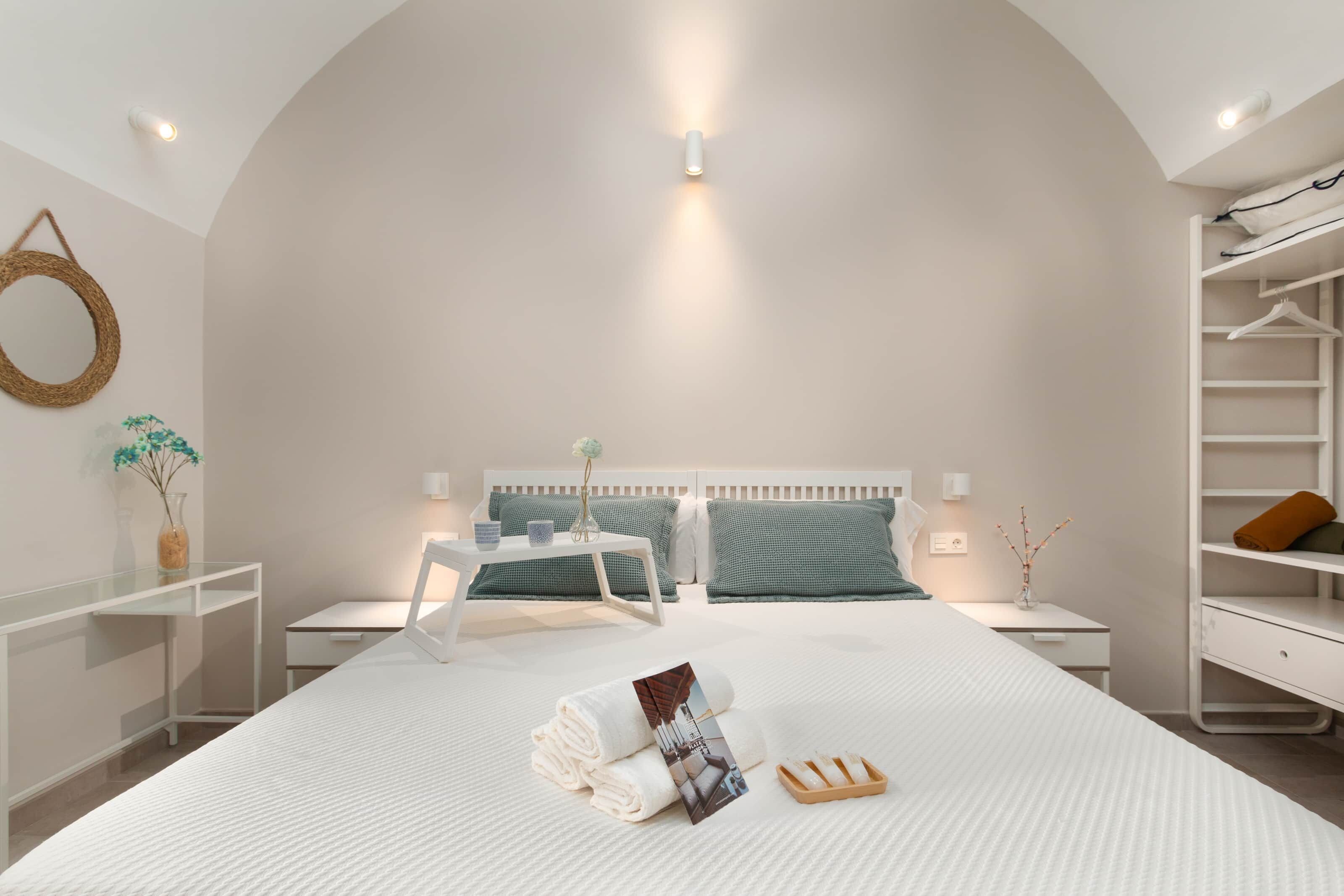 Een moderne slaapkamer met een groot bed, nachtkastjes, een kledingkast en een hanglamp.