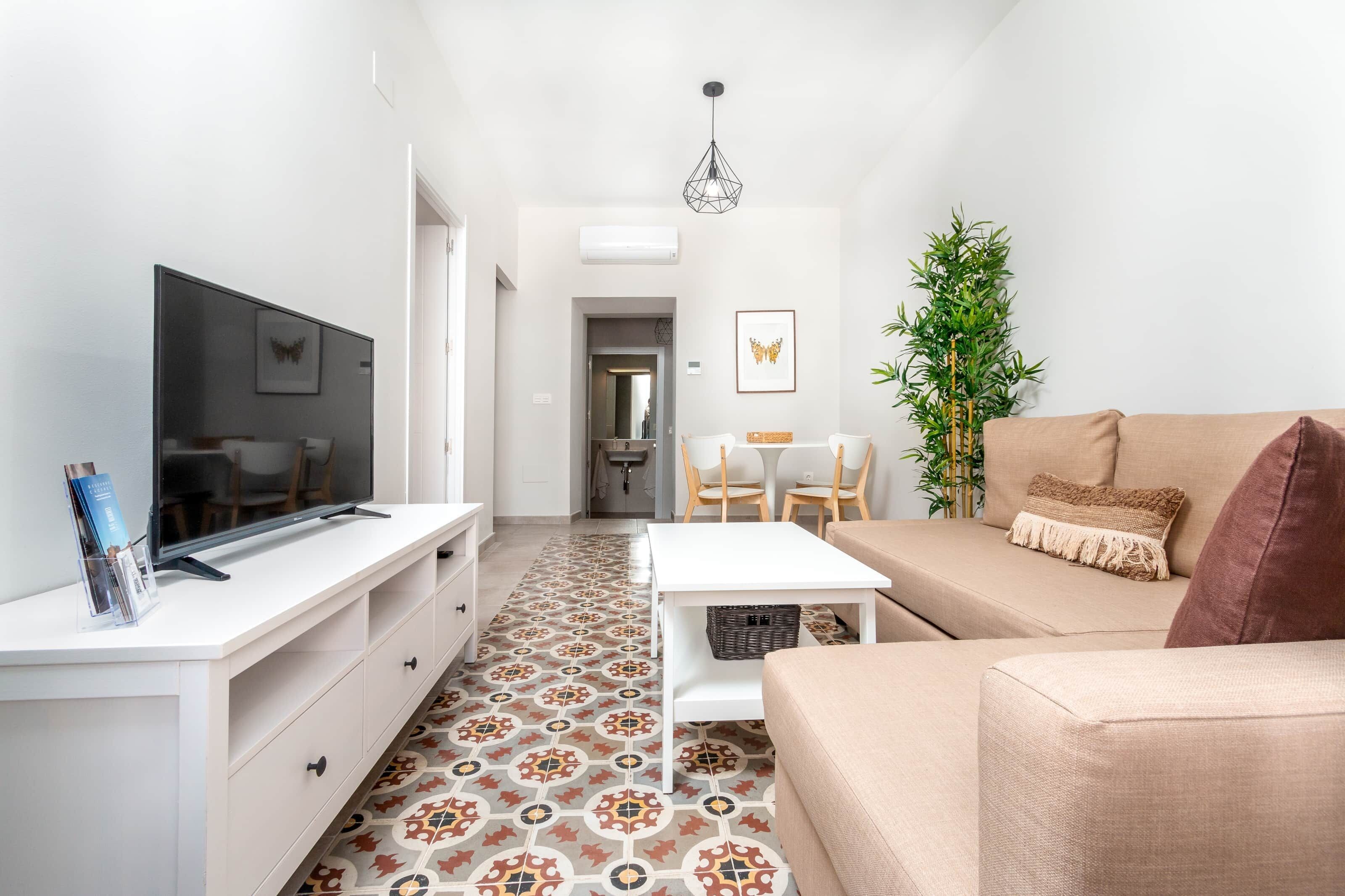 Un salon moderne doté d’un téléviseur à écran plat, d’un canapé, d’une table basse et d’un coin repas avec des chaises.
