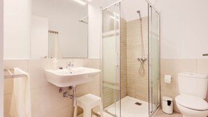 Une salle de bain moderne avec une douche à parois de verre, un lavabo blanc et des toilettes.