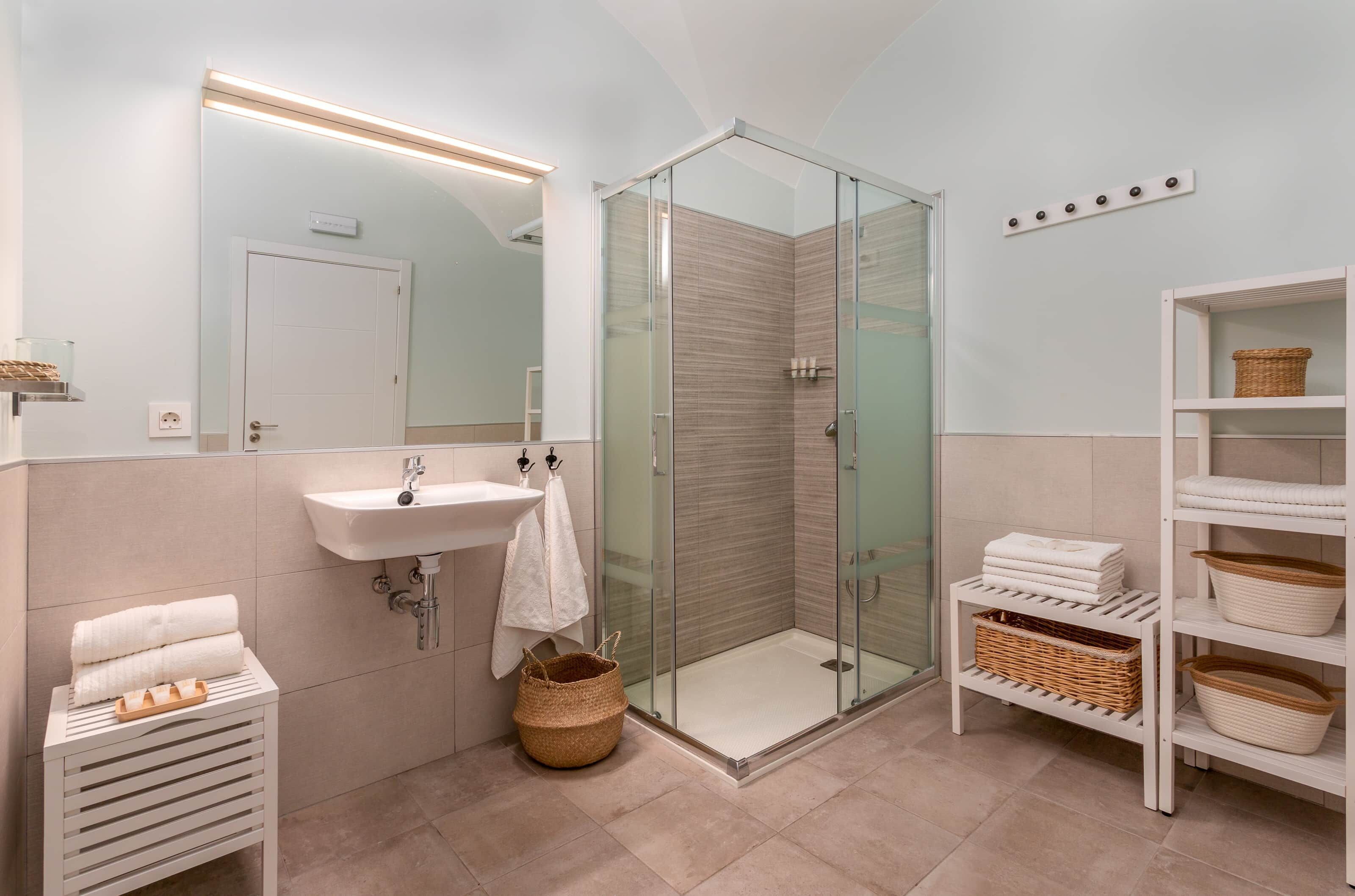 Un baño moderno con cabina de ducha de vidrio, un lavabo y tocador con toallero.