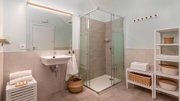 Un baño moderno con cabina de ducha de vidrio, un lavabo y tocador con toallero.