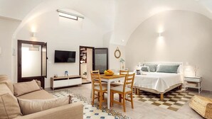 Une chambre d’hôtel de taille réduite comprenant un lit, un canapé, une table à manger avec des chaises, un téléviseur et une petite table d’appoint.