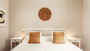 Ein ordentlich eingerichtetes Schlafzimmer mit einem großen Bett, zwei Nachttischen und einer runden Wanddekoration.