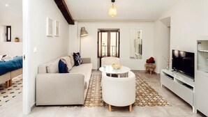 Ein modernes Wohnzimmer mit einer Couch, einem Couchtisch, einem Fernseher und einem gemusterten Teppich.