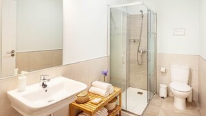 Ein modernes Badezimmer mit einer Duschkabine aus Glas, einem weißen Waschbecken und einer Toilette.