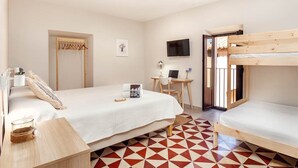 Un dormitorio con una cama individual doble, un escritorio con silla, un televisor y una ventana con vistas.