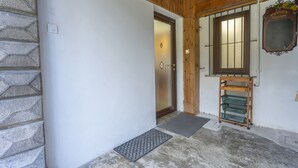 A wooden door with a glass panel, a small mat at the entrance, and a wooden shelf with baskets. - Hladik House - Alpi Giulie Cosy Apartment (Tarvisio)