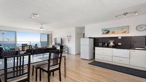 Ein moderner Wohnraum mit Essbereich, Küche und großem Fenster mit Meerblick.