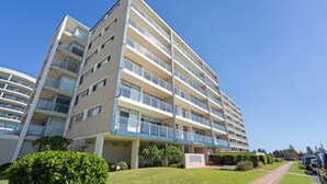 Ein mehrgeschossiges Hotel mit Balkonen, einem überdachten Eingang und einem gepflegten Rasen.