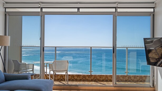 Ein Balkon mit Blick auf den Ozean, einer Couch und zwei Stühlen.