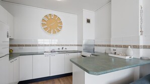 Eine Küche mit weißen Schränken, einer Holz-Uhr und einer gefliesten Spritzschutzwand.