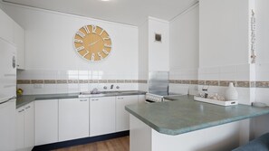 Una cocina con armarios blancos, un reloj de madera y un salpicadero de azulejos.
