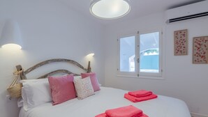 A neatly made bed with pink towels, white bedding, and decorative pillows. - Maison de Pécheurs à 1mn à Pied de la Plage Cala Alcaufar (Alcaufar)