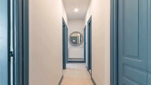A hallway with a light-colored carpet, blue doors, and a round mirror on the wall. - KUIA apartment in Barakaldo, next to the metro (Barakaldo)