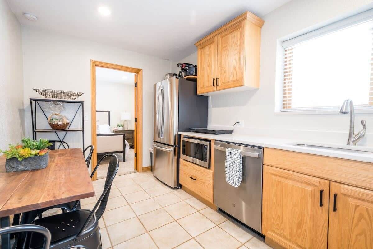A modern kitchen with wooden cabinets, stainless steel appliances, and a dining area with a table and chairs.