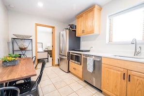 A modern kitchen with wooden cabinets, stainless steel appliances, and a dining area with a table and chairs.