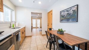 Een moderne keuken met een houten eettafel, zwarte stoelen en een schilderij aan de muur.