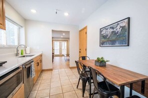 A modern kitchen with a wooden dining table, black chairs, and a painting on the wall. - 1BR I Hidden Falls I Brighton Ski Resort (Salt Lake City)