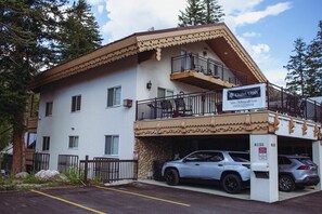 A two-story building with a balcony on the upper floor, a sign for Chalet Utah, and a parking area with two cars. - 1BR I Hidden Falls I Brighton Ski Resort (Salt Lake City)