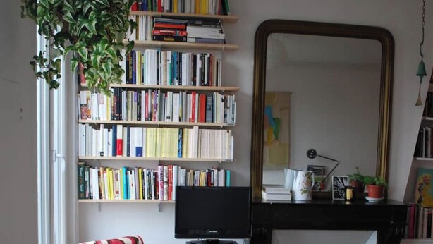 Ein gemütliches Wohnzimmer mit Kamin, einer Bücherwand voller Bücher, einem bequemen Sessel und einem Fernseher.
