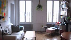 Ein Wohnzimmer mit einer Couch, einem Couchtisch, einem Sessel, einem kleinen Tisch und einem Bücherregal.
