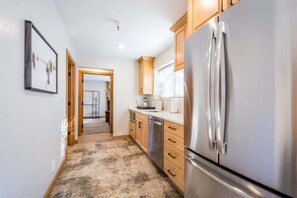 A modern kitchen with wooden cabinets, a stainless steel refrigerator, and a dishwasher.