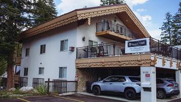En tvåvåningsbyggnad med en balkong, en skylt med texten ”Chalet Utah” och en parkeringsplats med plats för två bilar.