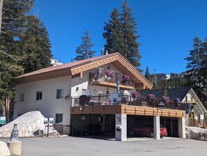 A two-story building with a balcony, a garage, and a parking area.