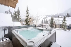 Una vasca idromassaggio su un balcone con vista su una montagna innevata.