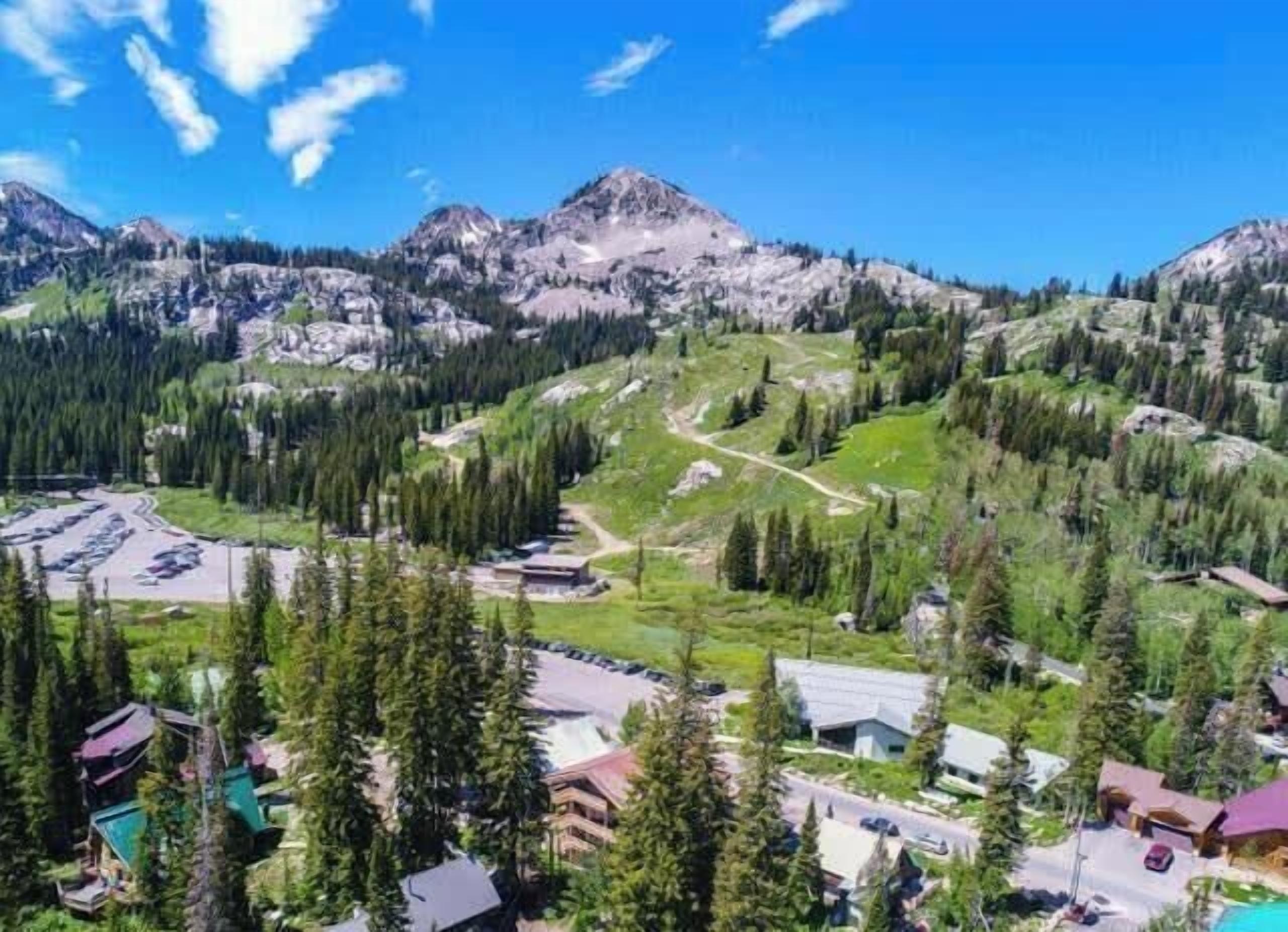 A mountainous landscape with a parking area, buildings, and a road.