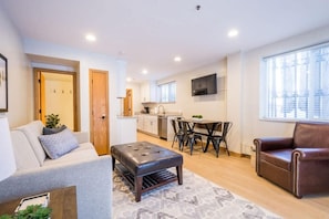 Un appartement moderne comprenant un salon, un coin repas, une kitchenette et une grande fenêtre.