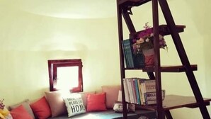 A living room with a sofa, a coffee table with plates, a bookshelf, and a ladder.