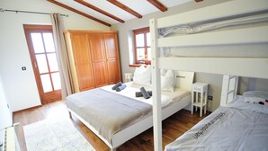 Una habitación con literas, un armario de madera, una mesita de noche pequeña y una ventana con cortinas.