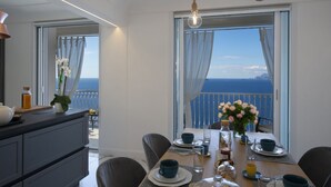 A dining area with a view of the sea, a wooden table set with plates, cups, and a vase of flowers. - Terrazze di Laurito, at 3 kms from Positano (Positano)