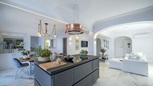A modern kitchen with a central island, pendant lighting, and a white dining area. - Terrazze di Laurito, at 3 kms from Positano (Positano)