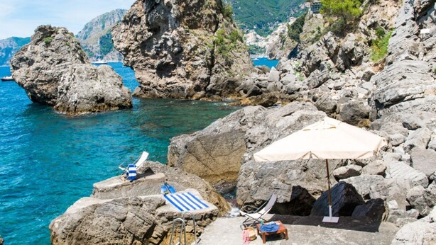A rocky coastal area with clear blue water, a beach chair, a sun umbrella, and a small table with a towel. - Terrazze di Laurito, at 3 kms from Positano (Positano)