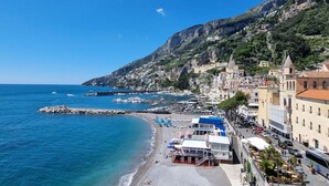A coastal town with a beach, buildings, and a rocky hillside. - Dolce Vita B by Amalfi Beaches (Amalfi)