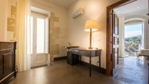 Ein Zimmer mit Schreibtisch, Lampe, Waschbecken und Blick auf einen Balkon.