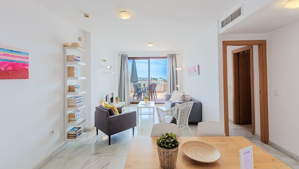 Una sala de estar moderna con un sofá, sillones, una mesita de centro y una estantería.