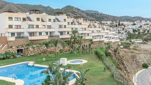 Un edificio residencial con varios balcones, una piscina y un jardín ajardinado.
