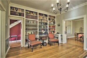 Une bibliothèque avec des étagères, deux chaises, une table et un escalier.